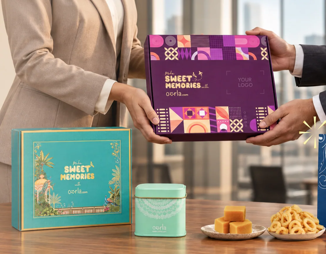 Two colleagues exchanging an Oorla gift box across a desk, beside a teal keepsake box, a printed tin and a branded carrier