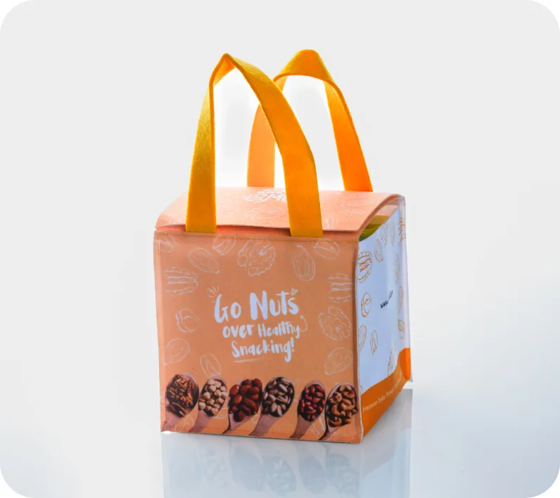 An orange cube gift box with fabric carry handles, printed “Go Nuts over Healthy Snacking!” with illustrated nuts