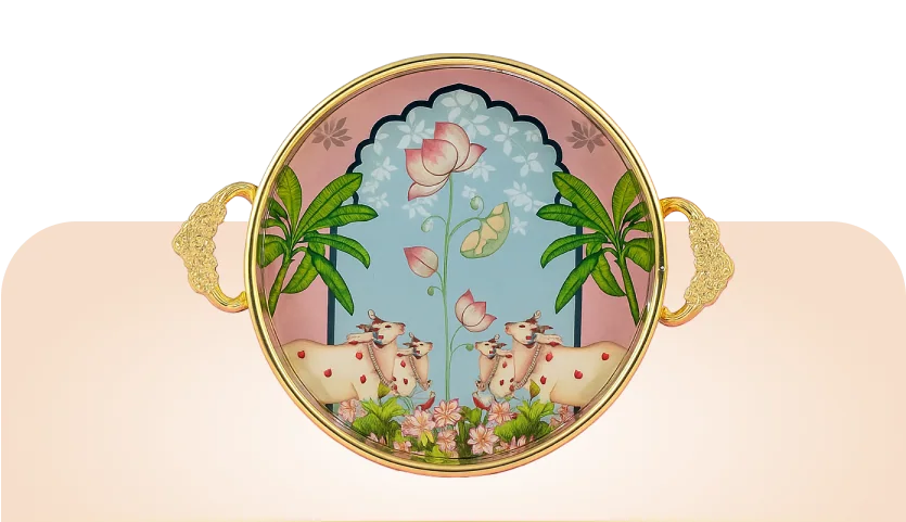 Pichwai Return Gifts: a round enamel tray with gold cast handles, painted with cows, palms and a lotus in the Pichwai style.