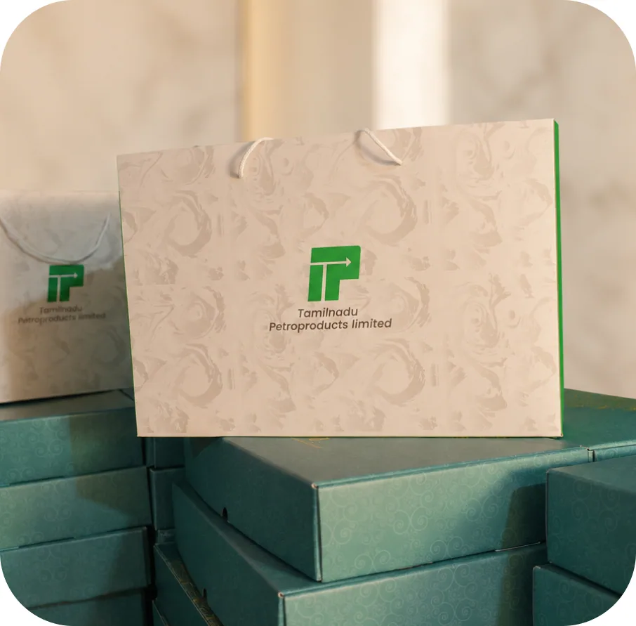 A Tamilnadu Petroproducts marbled carry bag standing on stacks of teal sweet boxes